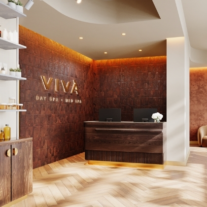 Viva Day Spa + Med Spa reception with dark wood walls, gold Viva logo, front desk, retail shelves, and herringbone wood floor