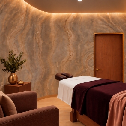 Massage treatment room at Viva Day Spa + Med Spa in Atlanta, Georgia with backlit stone wall, massage table, and cozy lounge chair