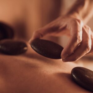 Polished basalt stones being placed along the spine during a Natural Body hot stone massage treatment.