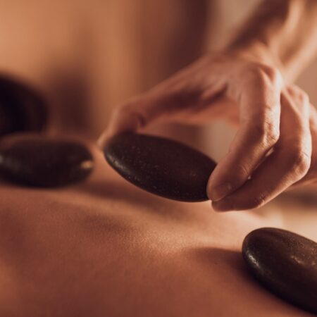 Polished basalt stones being placed along the spine during a Natural Body hot stone massage treatment.