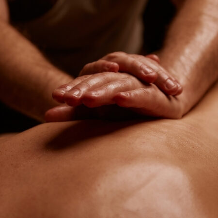 Hands gently pressing into a guest's back during a professional massage session.