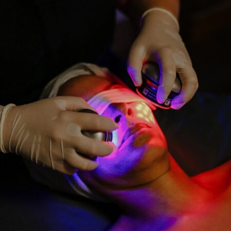 Client receiving LED red and blue light therapy while lying down during advanced skincare treatment