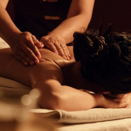 Massage therapist working into a woman's shoulder muscles using a therapeutic technique.