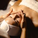 Woman with dewy and glowing skin enjoying a facial massage at Natural Body Spa.