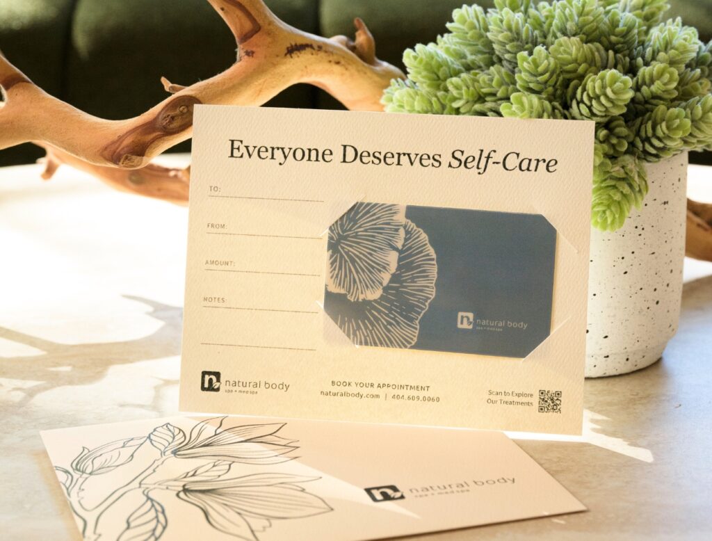 Natural Body Spa and Med Spa Gift Card on table in spa lobby in with a succulent and driftwood.