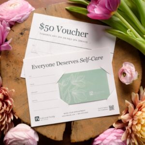 Natural Body Spa Gift Card and 50 dollar spa voucher placed on wood table with spring flowers